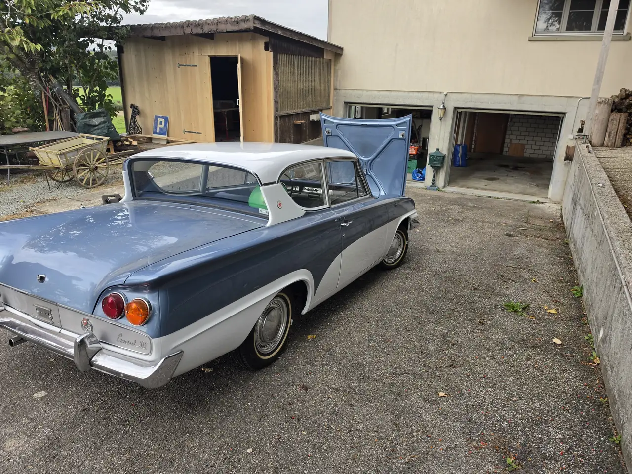 Blau-weisser Klassiker mit offener Motorhaube vor einer Garage