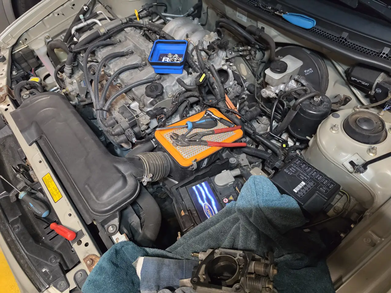 Geöffneter Motorraum bei einem Service, ausgebauter Luftfilter mit Werkzeug darauf